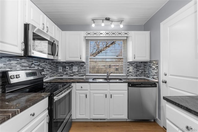 kitchen featuring stainless steel appliances, white cabinetry, sink, and decorative backsplash