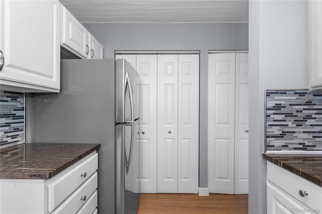 kitchen with white cabinetry, decorative backsplash, stainless steel fridge, and hardwood / wood-style flooring