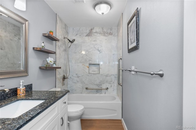 full bathroom with vanity, wood-type flooring, tiled shower / bath, and toilet