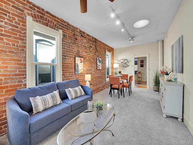 living area with light carpet, track lighting, brick wall, and ceiling fan