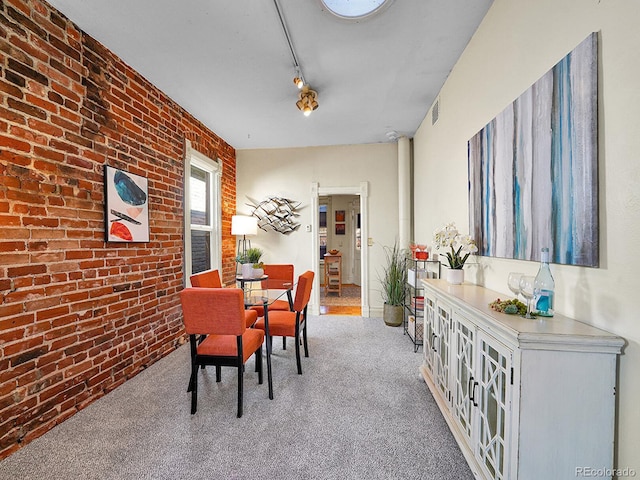 carpeted dining area with track lighting, brick wall, and visible vents