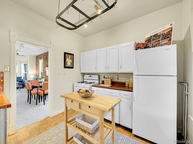 kitchen featuring white appliances, white cabinets, and wooden counters