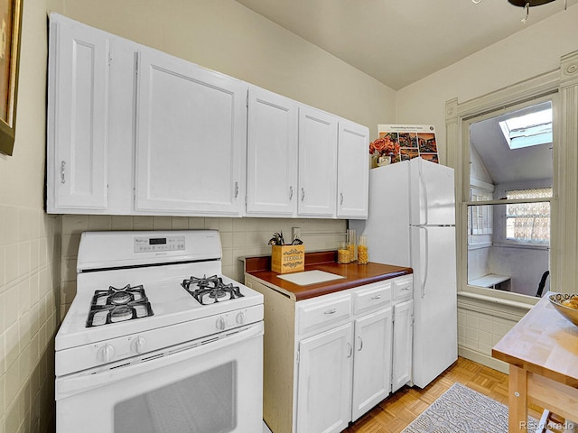 kitchen featuring white appliances, white cabinets, and lofted ceiling with skylight