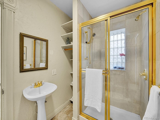 bathroom with baseboards, a stall shower, and a sink