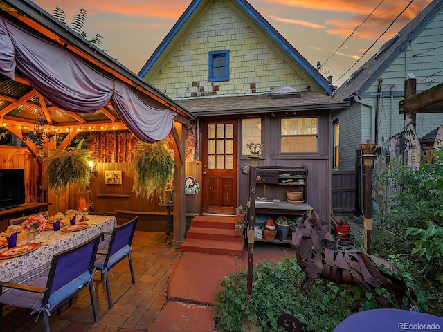 exterior space with fence, roof with shingles, and a patio area