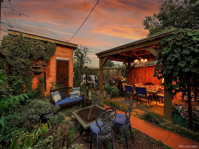 patio terrace at dusk featuring a gazebo, fence, and an outdoor fire pit