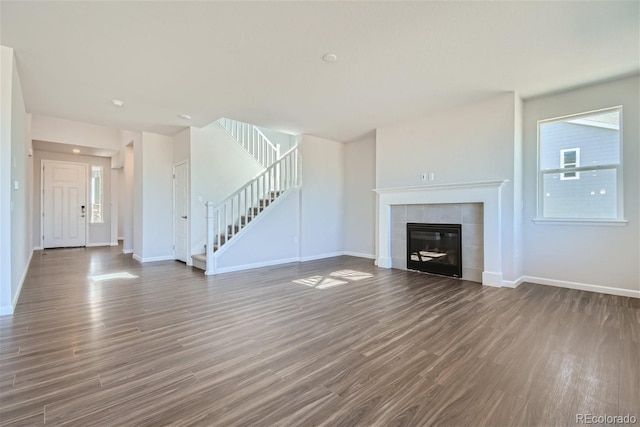 unfurnished living room featuring a tile fireplace and dark hardwood / wood-style floors