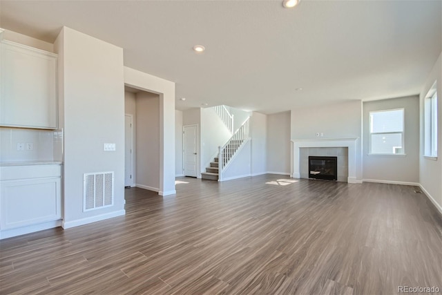 unfurnished living room featuring a tile fireplace and hardwood / wood-style floors