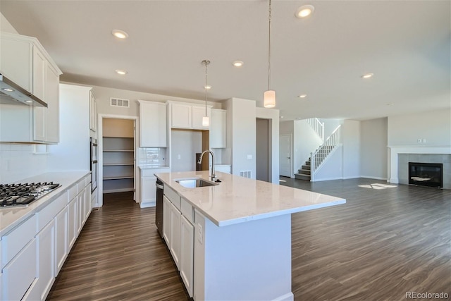 kitchen with white cabinetry, sink, hanging light fixtures, an island with sink, and appliances with stainless steel finishes