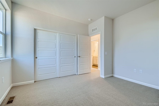 unfurnished bedroom with light colored carpet and a closet