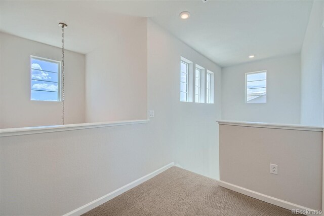 carpeted spare room with an inviting chandelier