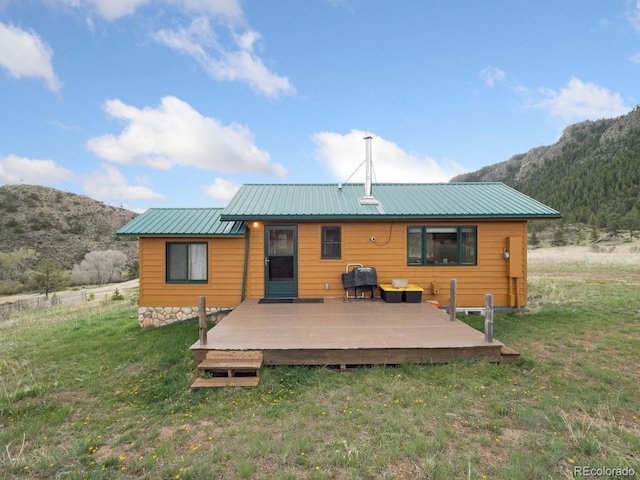 back of house featuring a deck with mountain view and a yard