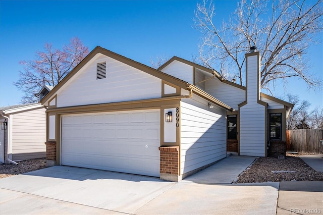 view of front of house featuring brick siding, a chimney, fence, a garage, and driveway