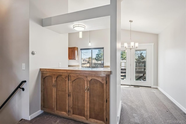 kitchen with lofted ceiling, baseboards, dark colored carpet, and a notable chandelier