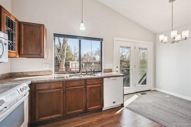 kitchen featuring lofted ceiling, white appliances, a sink, and hanging light fixtures