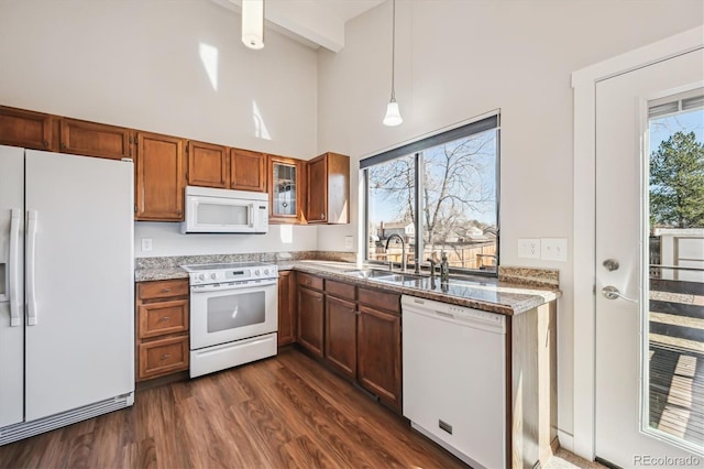 kitchen featuring white appliances, glass insert cabinets, dark wood-type flooring, a high ceiling, and a sink