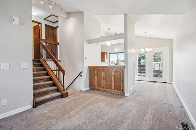 interior space featuring light colored carpet, baseboards, vaulted ceiling, an inviting chandelier, and track lighting