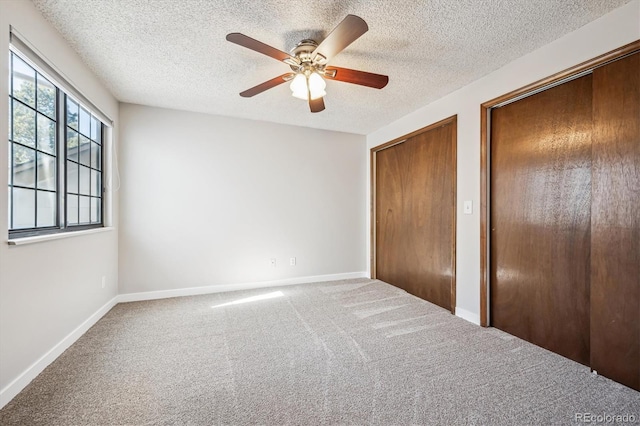 unfurnished bedroom with carpet floors, a textured ceiling, baseboards, and a ceiling fan