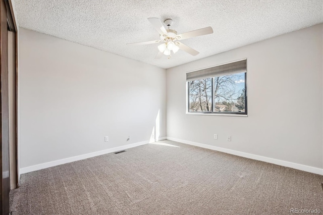 carpeted empty room featuring visible vents, ceiling fan, a textured ceiling, and baseboards