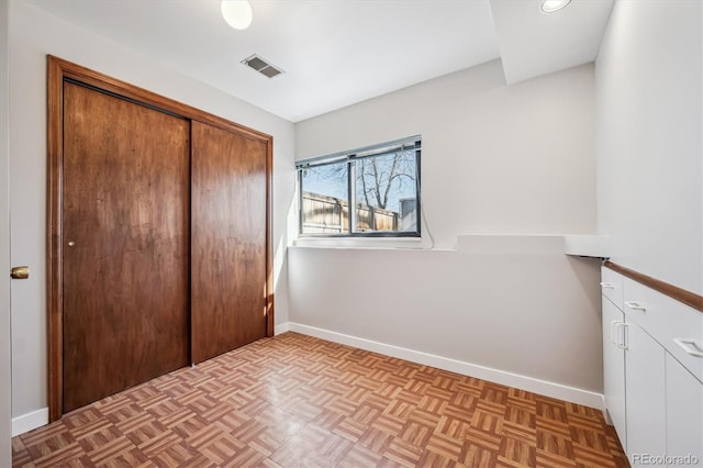 unfurnished bedroom with a closet, visible vents, and baseboards