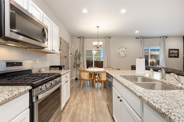 1108 Huntington Ave, Dacono, CO 80514 - kitchen with stainless steel appliances, a chandelier, white cabinets, light wood finished floors, and recessed lighting