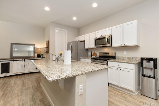 1108 Huntington Ave, Dacono, CO 80514 - kitchen featuring appliances with stainless steel finishes, light wood-type flooring, white cabinetry, light stone counters, and recessed lighting