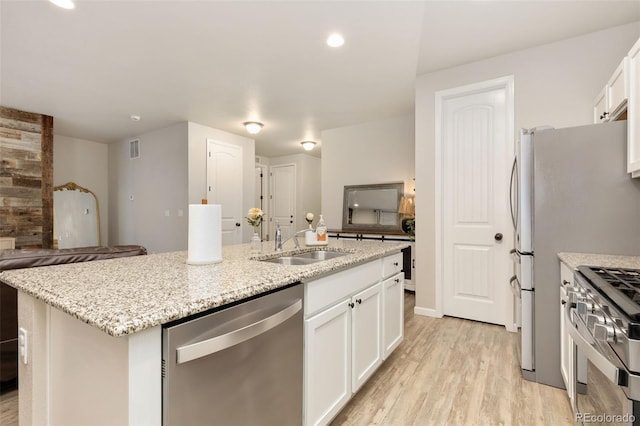 1108 Huntington Ave, Dacono, CO 80514 - kitchen featuring stainless steel appliances, an island with sink, light wood-style floors, white cabinets, and recessed lighting