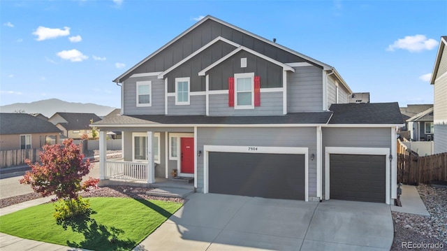 view of front of home featuring a porch, fence, concrete driveway, board and batten siding, and a front yard