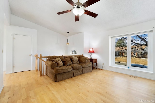 living room with lofted ceiling, light hardwood / wood-style flooring, and a textured ceiling