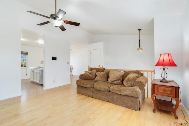 living room featuring vaulted ceiling, ceiling fan, and light wood-type flooring