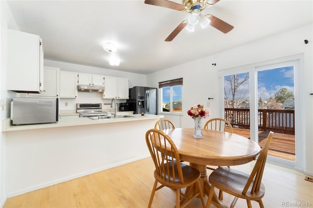 dining space featuring ceiling fan, sink, and light wood-type flooring