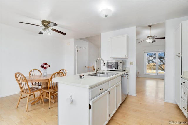 kitchen with light wood-type flooring, stainless steel dishwasher, sink, and white cabinets