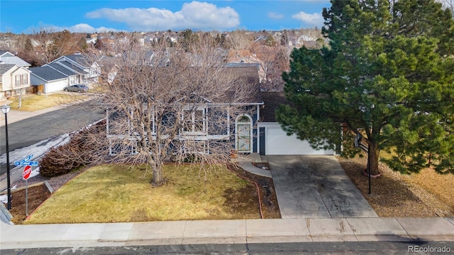 view of property hidden behind natural elements featuring a garage and a front lawn