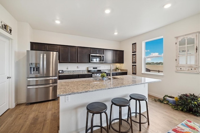 353 Raven Ln, Johnstown, CO 80534 - kitchen featuring appliances with stainless steel finishes, dark brown cabinetry, light wood-type flooring, a breakfast bar, and recessed lighting