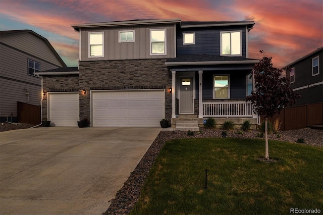 353 Raven Ln, Johnstown, CO 80534 - view of front facade featuring stone siding, a porch, a lawn, driveway, and a garage