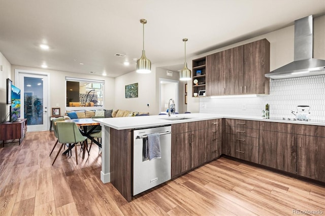 kitchen with sink, stainless steel dishwasher, light hardwood / wood-style floors, kitchen peninsula, and wall chimney exhaust hood