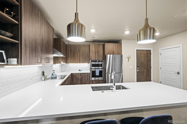 kitchen featuring sink, hanging light fixtures, stainless steel appliances, and a breakfast bar