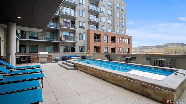 view of pool featuring exterior kitchen, a mountain view, and area for grilling