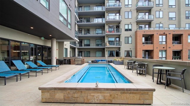 view of pool featuring exterior bar and a hot tub