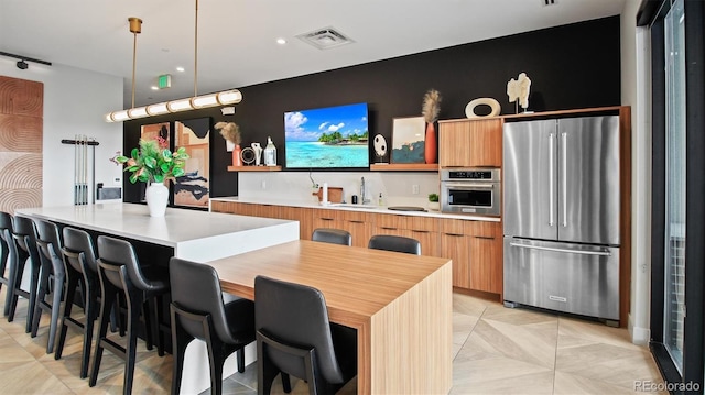 kitchen featuring sink, a breakfast bar area, stainless steel appliances, decorative light fixtures, and kitchen peninsula