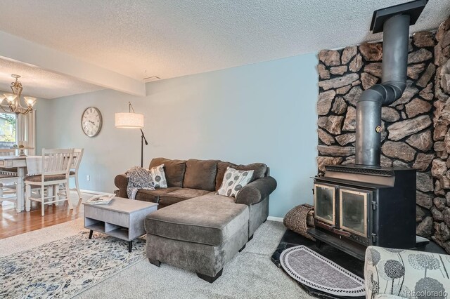 living room with a textured ceiling, wood-type flooring, an inviting chandelier, and a wood stove