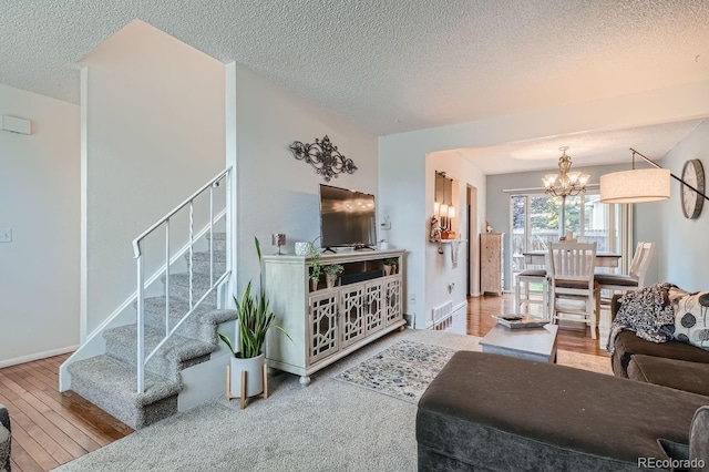 living room featuring a notable chandelier, wood-type flooring, and a textured ceiling