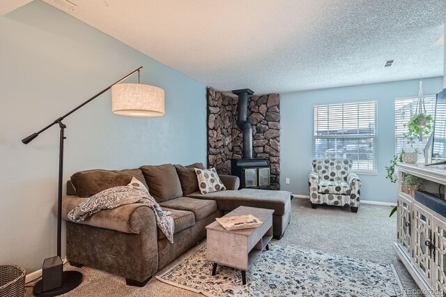 carpeted living room with a textured ceiling and a wood stove