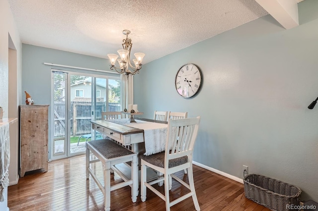 dining area with an inviting chandelier, a textured ceiling, and hardwood / wood-style floors