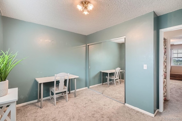 carpeted home office featuring a textured ceiling