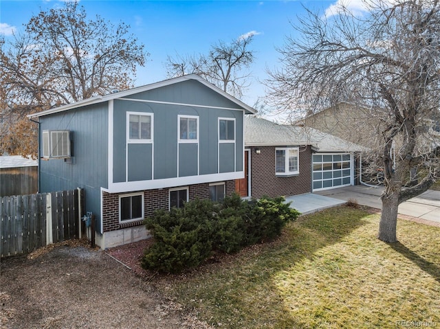 split level home with brick siding, concrete driveway, fence, a garage, and a front lawn