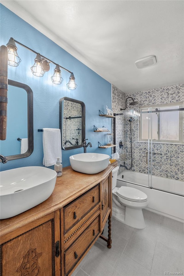 full bathroom with combined bath / shower with glass door, a sink, toilet, and double vanity