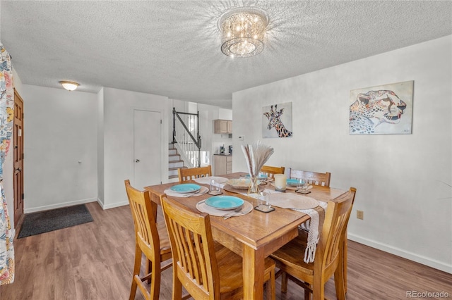 dining room with baseboards, a notable chandelier, stairway, and wood finished floors