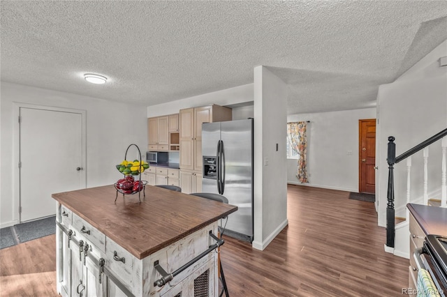 kitchen featuring baseboards, dark countertops, wood finished floors, a center island, and stainless steel appliances