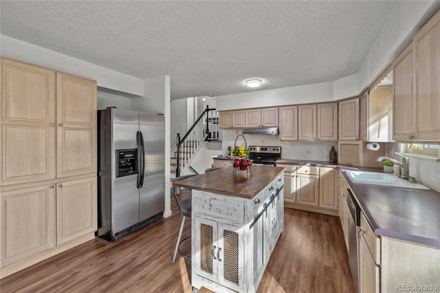 kitchen with appliances with stainless steel finishes, a center island, light brown cabinets, and a sink